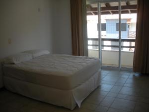 a bed in a bedroom with a large window at Fragata Azul Casa in Bombinhas