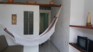 a hammock hanging in a room with a tv at Flat Matriz in Viçosa do Ceará