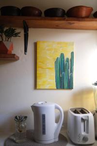 a kitchen counter with a coffee maker and a cactus painting at Tilcara Mistica Hostel in Tilcara