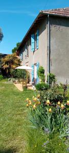 a house with a yard with flowers and an umbrella at La Yourte Gasconne in Estampures