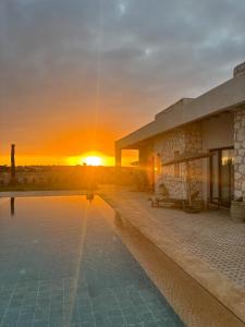 a building with a pool in front of a sunset at Tempo Vegan B&B in Essaouira