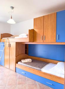 a bunk bed with blue walls and wooden cabinets at La Ginestra - Casa Vacanze in Porto Alabe