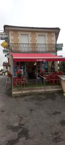 a restaurant with red tables in front of a building at Le Café D Ici in Saillat-sur-Vienne
