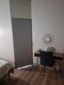 a bedroom with a desk and a door with a table and a chair at Le Café D Ici in Saillat-sur-Vienne