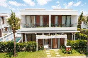 an exterior view of a house with a palm tree at Sea La Vie Beachfront Villa - Bai Truong Beach Phu Quoc in Phú Quốc +31 photos