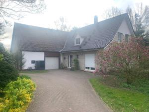 a white house with a gray roof and a driveway at FeWo Naturblick mitten im schönen Cuxland Perfekt für Familien mit Hunden in Stinstedt