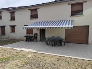 a patio with tables and chairs and a blue and white awning at Dépaysement à la campagne in Saint-Martin-de-Sanzay