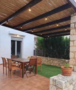 eine Terrasse mit Tisch und Stühlen unter einer Holzpergola in der Unterkunft Urania Luxury Suite with pool view -Loutra Resort in Loutra