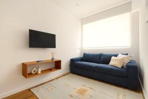 a living room with a blue couch and a flat screen tv at Home on Rua da Alegria in Bicas