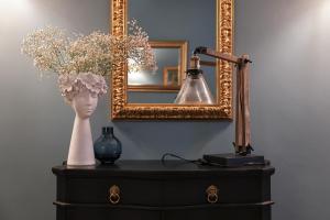 a table with a lamp and a mirror and a vase with flowers at Ca' Perdon Apartment in Venice