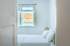 a white room with a window and a bed at Thavma Kalosyni in Firopótamos