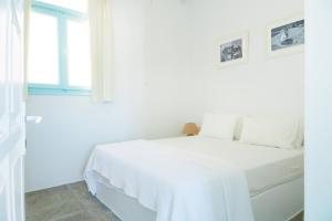 a white bedroom with a white bed and a window at Thavma Kalosyni in Firopótamos