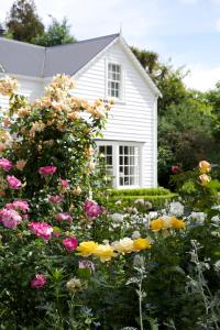 a garden of flowers in front of a white house at Wyett Annex in Greytown