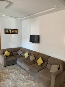 a living room with a brown couch and a flat screen tv at Azla Beach Escape - Cozy Apartment in Tétouan +2 photos