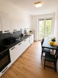 a kitchen with white cabinets and a dining table at Centrum apartment in Brno