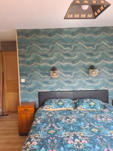 a bedroom with a bed and a painting on the wall at Les Orchidées - chambres d'hôtes in Surtainville