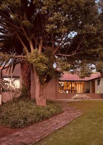 a tree in the grass next to a house at Origin Cottage in eMalahleni