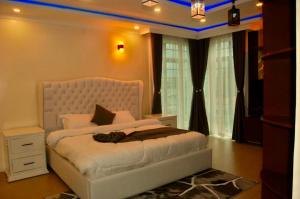 a bedroom with a white bed in a room with windows at Villaveh Gameview in Nakuru