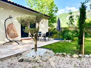a garden with a tree and a patio at L'Écrin d'Ussat in Ussat
