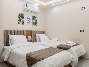 two beds in a room with white walls at Pool view- Luxurious 3BD Hotel Apt, Sheikh Zayed in Kafr Abū ʼumaydah +29 photos