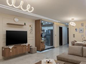 a living room with a television and a couch at Pool view- Luxurious 3BD Hotel Apt, Sheikh Zayed in Kafr Abū ʼumaydah