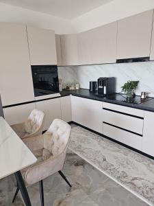 a kitchen with white cabinets and a table and chairs at Villa Nova Bar in Bar