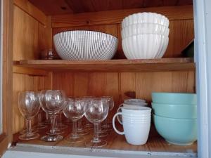 a shelf with bowls and cups and wine glasses at Charming house in Montbron