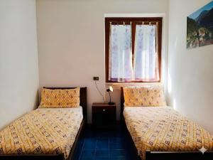 two beds in a room with a window at Casa Bepi balcone in Mezzolago
