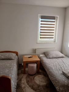a bedroom with two beds and a table with a window at Klara in Tomislavgrad