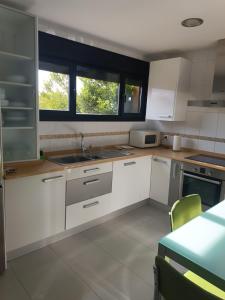 a kitchen with white cabinets and a sink and two windows at La Vega in Cardeñadijo