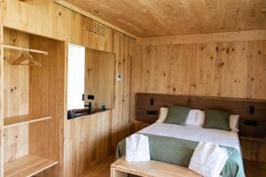 a bedroom with a bed and a wooden wall at Cabanas do Navia in Coea
