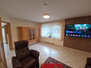 a living room with a chair and a large screen tv at Gartentraum in Papenburg