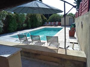 two chairs and an umbrella next to a swimming pool at Le Val du Pyrate Petit déj compris, piscine, parking in Colonzelle +15 photos