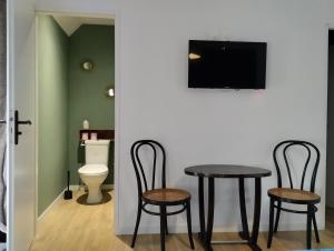 two chairs and a table in a room with a toilet at Chambres d'hôtes du Chênelong Cantal in Marchastel