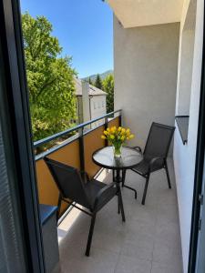 a balcony with a table and chairs and a vase of flowers at Apartmán centrum BB s balkónom a parkovaním in Banská Bystrica