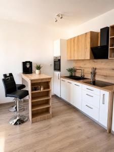 a kitchen with white cabinets and a black chair at Apartmán centrum BB s balkónom a parkovaním in Banská Bystrica