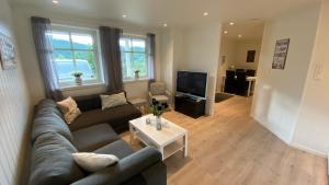 a living room with a couch and a tv at Vetlebekken Apartment close to Trolltunga in Steinaberg +30 photos
