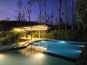 a swimming pool in a garden with a pavilion at Corbett Mid Forest House - 1 Min Walk from Dabka River in Rāmnagar +74 photos