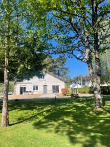 a white house with trees in the grass at Chambre 24h Le Mans in Guécélard