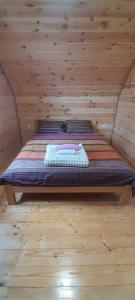 a bed in a room with a wooden wall at MANN House in Ninkovići