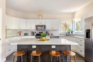 a kitchen with white cabinets and a large island with stools at Prospect Haus Stone Oak in San Antonio