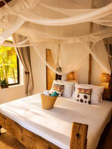a bedroom with a canopy bed with white sheets and pillows at Karibuni Marafiki in Bwejuu