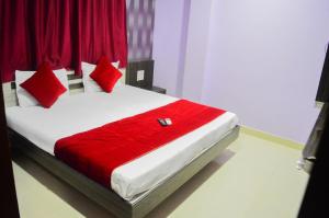 a bedroom with a bed with red sheets and pillows at Hotel Royal Palace in Ujjain