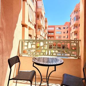 a table and chairs on a balcony with a table at 2BR Apt with Pool View in City Center in Oulad Akkou