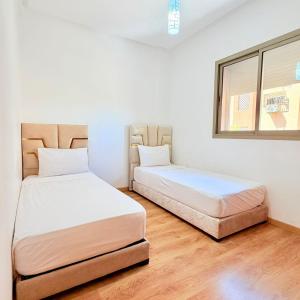 two beds sitting next to each other in a room at 2BR Apt with Pool View in City Center in Oulad Akkou