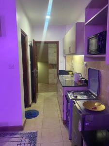 a purple kitchen with a stove and a sink at West suites kisauni road in Nairobi