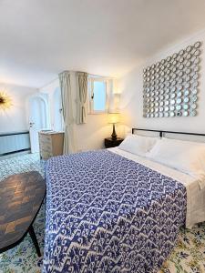 a bedroom with a blue and white bed and a table at Villa Sain Charming Suite in Anacapri