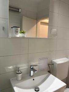 a white bathroom with a sink and a mirror at Apartman Mila in Split