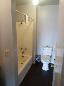 a bathroom with a toilet and a bath tub at The Coalinga Motel in Coalinga +31 photos