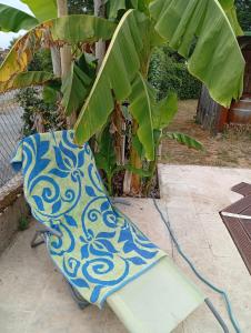a blue and white chair next to a banana tree at Mady in Villeneuve-sur-Lot